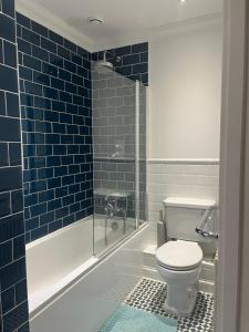 ein Bad mit einem WC und einer Dusche mit blauen Fliesen in der Unterkunft Life's A Beach - cosy, luxury cottage in Ashley Cross, Poole in Parkstone + 27 Fotos