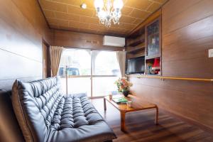 a living room with a leather couch and a table at 甲府木ノ間Kofu Konoma in Kofu