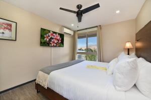 a bedroom with a white bed and a window at Nani Kai Hale 605 · NKH 605 Remodeled BeachFront w Pool AC Sandy in Kihei +52 photos