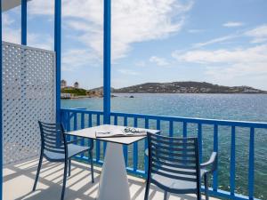 a table and chairs on a balcony overlooking the water at Bluetopia Suites in Mýkonos City