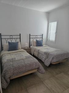 two beds in a white room with a window at Barloveto 3 apartament in Playa Honda
