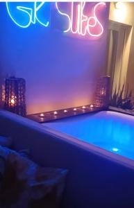 bañera de hidromasaje en una habitación con un cartel de neón en Gk Suites-Constantin view , auto check-in 24h, en Larisa