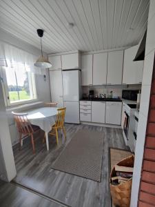 Una cocina con gabinetes blancos y una mesa y sillas. en Koivistonpiha farmstay, en Valkeakoski