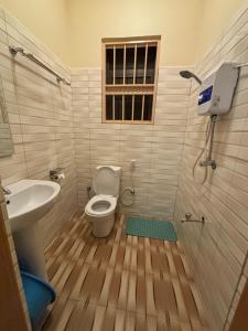 a bathroom with a toilet and a sink and a window at Albatina Place in Nakasongola