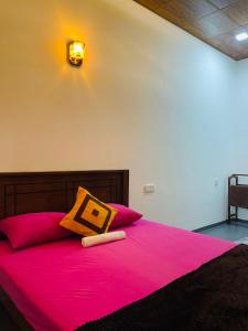ディックウェラにあるThe Sandora Villaのピンクのシーツとオレンジ色の枕が置かれたベッドのある寝室