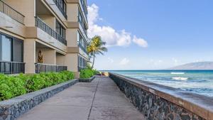a walkway next to a building next to the ocean at Maui Kai 808 · MK 808 OceanFront 1BD Kaanapali Beach Ocean Views in Lahaina