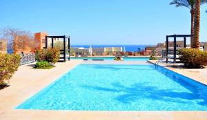 a large blue swimming pool with the ocean in the background at Azzura Sahl Hasheesh in Hurghada +22 photos