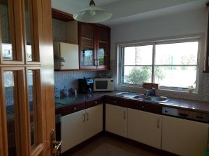 Una cocina con gabinetes blancos y un fregadero y una ventana. en EncostaOasis Townhouse, en Estibeira