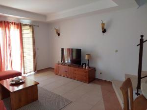 Una sala de estar con un televisor y una cruz en la pared. en EncostaOasis Townhouse, en Estibeira