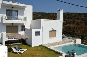 a white house with a swimming pool in the yard at Bianca Suite & Home in Psinthos