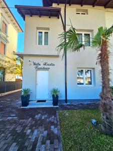 a white house with a white door and palm trees at Villa Kristin Residence in Monfalcone