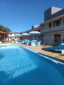 a large swimming pool with blue chairs and umbrellas at Pousada Caminho do Mar in Torres