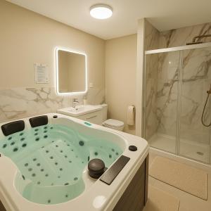 un bagno con vasca, WC e doccia di Evasion Romantique&Jacuzzi! a Pruniers