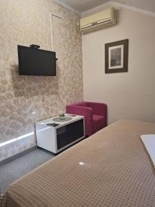 a room with a tv and a bed and a chair at Garni Hotel Ema in Kragujevac