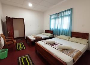 a bedroom with two beds and a chair and a mirror at Willwin Park in Anuradhapura