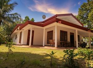 a small white house with a grass yard at Willwin Park in Anuradhapura