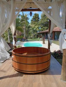a wooden hot tub in a pavilion next to a pool at Sítio por do Sol - Pedra Azul - ES in Pedra Azul
