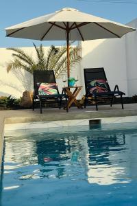 two chairs and an umbrella next to a swimming pool at Stylish and comfortable Villa Anna in Villaverde in Lajares