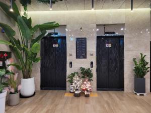 a lobby with two elevators with plants and trees at Hotel PIED Suseong in Daegu