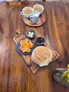 una mesa de madera con platos de comida y tazas de café en Cabaña en Rio Azul Campo Base, en El Bolsón 3 fotos más