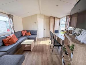 a living room with a blue couch and a kitchen at Great Caravan With Central Lounge & Wifi At Broadland Sands, Suffolk Ref 20070Bs in Hopton on Sea