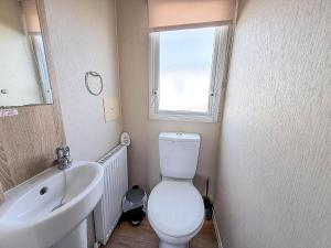 a bathroom with a white toilet and a sink at Great Caravan With Central Lounge & Wifi At Broadland Sands, Suffolk Ref 20070Bs in Hopton on Sea +17 photos