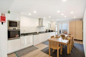 a kitchen with white cabinets and a wooden table at Quintinha das Achadas in Achadas da Cruz