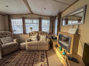 a living room with two chairs and a television at Ref 40035Nd - Superb Caravan With Decking & Free Wifi At North Denes Holiday Park in Lowestoft
