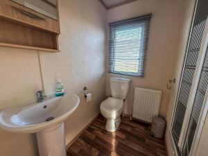 a bathroom with a white sink and a toilet at Ref 40035Nd - Superb Caravan With Decking & Free Wifi At North Denes Holiday Park in Lowestoft +16 photos
