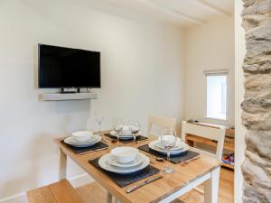 Un comedor con una mesa con platos y copas de vino. en Dyserth, en Clynnog-fawr