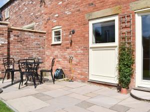 a patio with chairs and a white door and a brick building at White Heather Barn in Swanwick