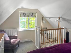 a bedroom with a staircase and a chair and a window at Mallards in Whepstead