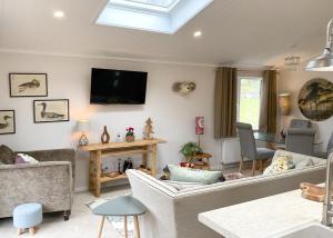 a living room with a couch and a tv on the wall at Clear Sky Lodge Park in Falstone +3 photos