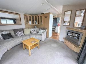 een woonkamer met een bank en een open haard bij Lovely 6 Berth Caravan With Decking At California Cliffs In Scratby Ref 50048L in Great Yarmouth +13 foto's