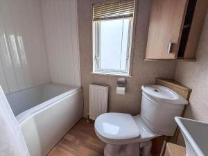 a bathroom with a toilet and a tub and a sink at Lovely 6 Berth Caravan With Decking At California Cliffs In Scratby Ref 50048L in Great Yarmouth +15 photos