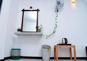 a mirror on a white wall with plants and a table at Village Breeze Cabana in Ella