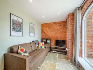 a living room with a couch and a brick wall at The Granary - Uk46002 in Rotsea