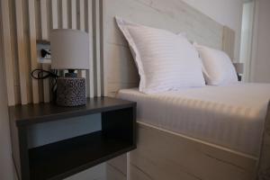 a bed with white pillows and a lamp on a table at Pensiunea Agroturistica Darius in Baia de Fier