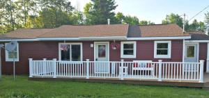 a small red house with a white fence at The Red Pine in Saint Ignace