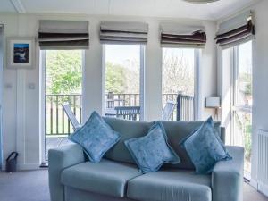 a blue couch in a living room with windows at Sunshine Lodge in Polperro