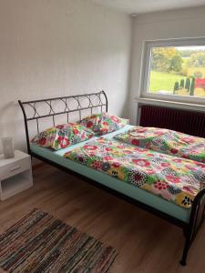 un letto con un piumone colorato in una camera da letto di Ferienwohnung Oberheuslingen a Freudenberg