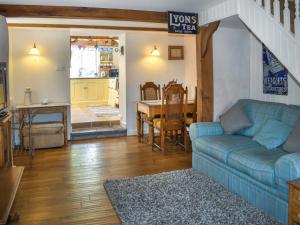ein Wohnzimmer mit einem blauen Sofa und einem Tisch in der Unterkunft Primrose Cottage in Seaton