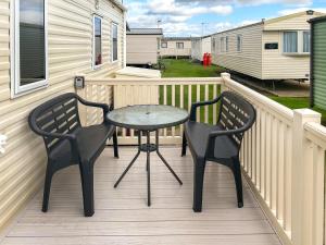 a patio with two chairs and a table on a deck at California Cliffs in Scratby