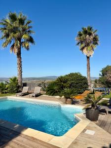a swimming pool with two palm trees in the background at Villa piscine privée superbe Vue Etang Leucate 8JBART580 in Port Leucate