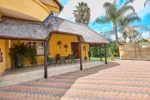 una casa gialla con tetto di paglia e patio di Twin Palms Guest House a Potchefstroom