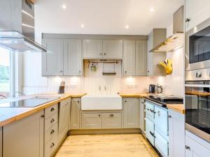 een keuken met witte kasten en een spoelbak bij Fred's Barn in Swanton Abbot +25 foto's