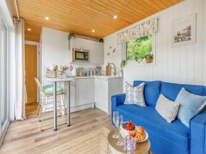 Una sala de estar con un sofá azul y una cocina. en Freedom Fields - Bluebell, en Straiton