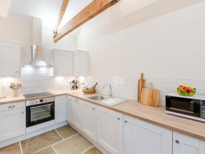 Una cocina con gabinetes blancos y un fregadero. en The Stables - Uk46003, en Rotsea