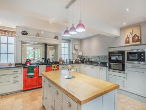 a large kitchen with white cabinets and red appliances at The Glebe in Heckington +15 photos