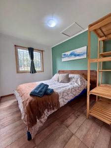 1 dormitorio con cama y escalera de madera en Cabaña en Rio Azul Campo Base, en El Bolsón